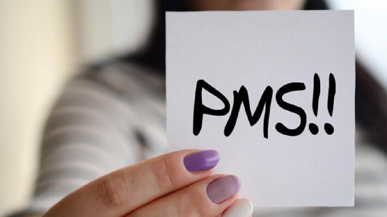 נערה מחזיקה פתק שכתוב עליו PMS